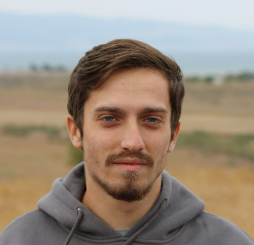 Portrait of a man with a beard standing outdoors.