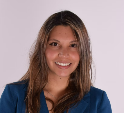 Smiling woman in a blue top on a plain background.